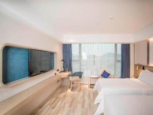 a hotel room with two beds and a large window at Kyriad Marvelous Hotel Foshan Xiqiao Mountain Scenic Area Qiaoling Square in Nanhai