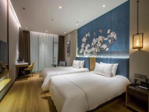 Ліжко або ліжка в номері Magnotel Business Hotel Zhenjiang South Station Greenland Square