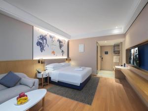 Kyriad Marvelous Hotel Bozhou Wanda Plaza في Bozhou: غرفه فندقيه بسرير واريكه
