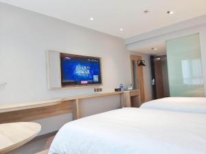 a hotel room with two beds and a flat screen tv at JinJiang Inn Zhenjiang Yangzhong Yangzi Road shop in Yangzhong