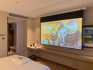 a large screen in a hotel room with a bed at Kyriad Marvelous Hotel Heyuan Wanlong City in Heyuan