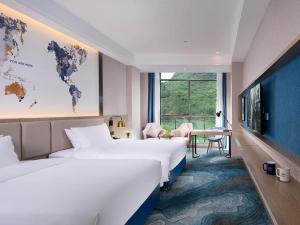 Kyriad Marvelous Hotel Hezhou Wanda Plaza في Hezhou: غرفة فندقية بسريرين و خريطة العالم على الحائط