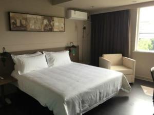 a bedroom with a large white bed and a chair at Jinjiang Inn Yangzhou Slender West Lake Dongguan Street in Yangzhou