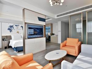 uma sala de estar com um sofá, uma televisão e uma cama em Kyriad Marvelous Hotel NanChang Xiang Lake Jinsha Avenue em Nanchang