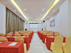 uma sala de conferências com mesas e cadeiras vermelhas e um ecrã em Vienna Hotel Danyang Glasses City High Speed Railway Station Dabo em Danyang