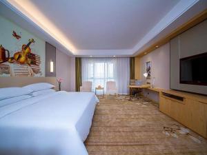 um quarto de hotel com uma cama grande e uma televisão em Vienna International Hotel Yichang Gezhouba Sanxia Culture Tiandi em Yichang