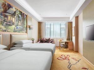 a hotel room with three beds and a television at Vienna International Hotel Zhejiang Wenzhou Ruian Tangxia in Ruian