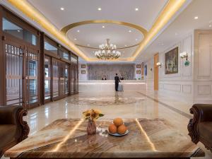 a lobby with a table and a man in the background at Vienna Hotel Huaidong Road Yuncheng in Yuncheng