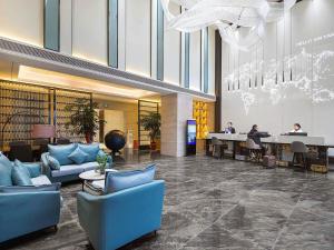 a lobby with blue furniture and people sitting at desks at Kyriad Marvelous Hotel Henan Xinyang Pingqiao Plaza in Xinyang