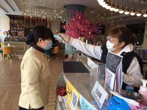 dos mujeres con máscaras parados en un mostrador en una tienda en Magnotel YangZhou China Grand Canal Museum Wanda Plaza en Yangzhou