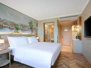 a bedroom with a large white bed and a television at Vienna Hotel Changsha Yuelu Mountain University city Xihu Park in Changsha