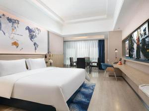 a hotel room with a large white bed and a desk at Kyriad Marvelous Hotel Changde Pedestrian Street in Changde