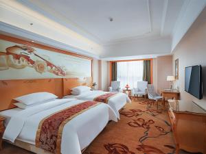 a hotel room with two beds and a flat screen tv at Vienna International Hotel Wuxi Huishan Yanqiao Metro Station in Wuxi