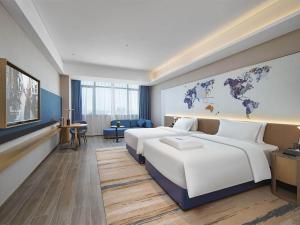 a hotel room with two beds and a map of the world at Kyriad Hotel Dongguan Houjie Convention and Exhibition Center Humen Station in Dongguan