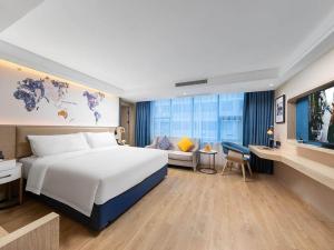 Cette chambre comprend un grand lit et une télévision. dans l'établissement Kyriad Marvelous Hotel Shenzhen Nanlian Metro Station, à Longgang
