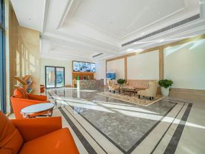 een grote lobby met oranje stoelen en een tafel bij Vienna Hotel Jiangyin Zhouzhuang in Jiangyin