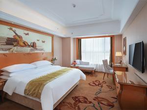 una camera con letto e TV a schermo piatto di Vienna International Hotel Wuxi Huishan Yanqiao Metro Station a Wuxi