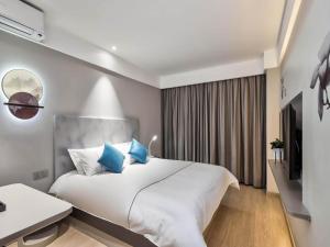 a bedroom with a large white bed with blue pillows at Magnotel Nanjing University of Aeronautics and Astronautics Shengtai West Road in Jiangning