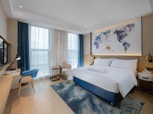 a hotel room with a large bed and a desk at Kyriad Marvelous Hotel Guilin Quanzhou in Quanzhou