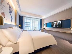 a hotel room with a large bed and a tv at Kyriad Marvelous Hotel Guizhou Dujun Center Wanda Plaza in Duyun