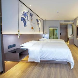 a bedroom with a large white bed with a map on the wall at Kyriad Marvelous Hotel Daya Bay BYD Technology Park in Huizhou