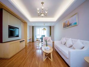 a living room with a white couch and a tv at Vienna International Hotel Yichang Gezhouba Sanxia Culture Tiandi in Yichang