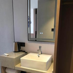 a bathroom with a white sink and a mirror at Kyriad Marvelous Hotel Daya Bay BYD Technology Park in Huizhou