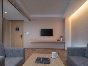 sala de estar con 2 sofás, mesa y TV en Kyriad Marvelous Hotel Dongguan Huangjiang Jingyi en Dongguan