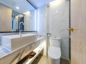 a white bathroom with a sink and a toilet at Kyriad Marvelous Hotel Changsha Xiangya in Changsha