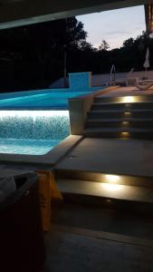 uma piscina à noite com um banco e luzes em Apartments Rafaj em Pula