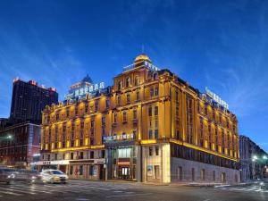 een groot geel gebouw in een stadsstraat 's nachts bij Kyriad Marvelous Hotel Harbin Railway Station Central Avenue in Harbin