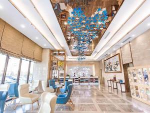 a large room with blue chairs and a chandelier at Kyriad Marvelous Hotel Weihai Railway Station in Weihai