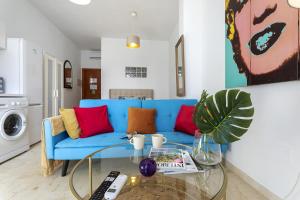 uma sala de estar com um sofá azul e uma mesa de vidro em -MalagaSunApts-Pop Dream CityCentre em Málaga