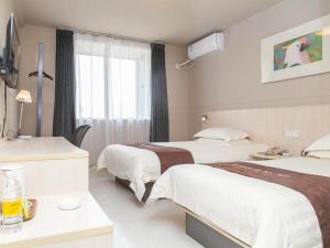 a hotel room with two beds and a window at Jinjiang Inn Zhenjiang Suzhou University Suning Plaza in Zhenjiang