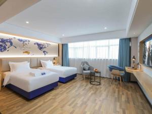 a hotel room with two beds and a desk at Kailyad Hotel Jiujiang Duchang Pedestrian Street in Duchang