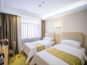 ein Hotelzimmer mit 2 Betten und einem Schreibtisch in der Unterkunft Vienna Hotel Harbin Train Station Jianguo Street in Harbin
