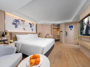 a hotel room with a bed and a table with oranges on it at Kyriad Marvelous Hotel Shenzhen Nanlian Metro Station in Longgang