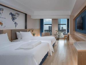 a hotel room with two beds and a large window at Kyriad Marvelous Hotel Huizhou South Station Danshui YI Center in Huizhou