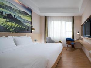ein Hotelzimmer mit einem großen Bett und einem TV in der Unterkunft Kyriad Marvelous Hotel Dongguan Huangjiang Jingyi in Dongguan