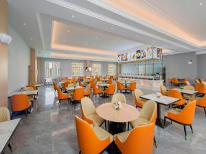 a restaurant with orange chairs and tables and a cafeteria at Vienna Hotels Yuncheng Hedong Street Wanda Store in Yuncheng