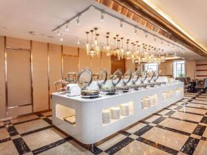 a buffet line with dishes and mirrors in a restaurant at Kyriad Marvelous Hotel Weihai Railway Station in Weihai