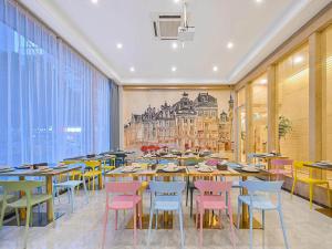 a restaurant with tables and chairs and a painting on the wall at Vienna Classic Hotel Wenzhou Cangnan High-Speed Railway Station Shop in Hengpu