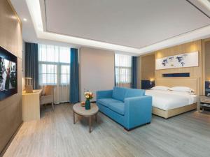 una camera d'albergo con un letto e un divano blu di Kyriad Hotel Baoying Jinyuan Square High-speed Railway Station a Baoying Altre 37 foto