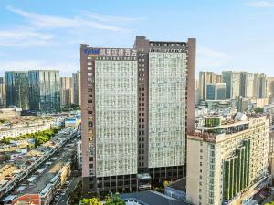 a large tall building in a city with buildings at Kyriad Hotel Jiujiang Happy City in Jiujiang