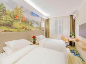 a hotel room with two beds and a painting on the wall at Vienna Classic Hotel Mudanjiang Railway Station in Mudanjiang