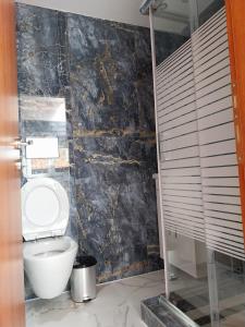baño con aseo y pared de piedra negra en OLGAS no2 HOUSE en Polýgyros