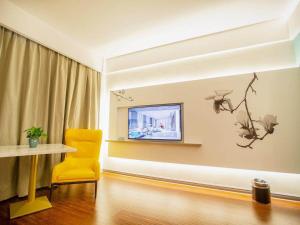 a living room with a yellow chair and a television at Magnotel Hotel Yangzhou Jinghua Wangyue Road in Yangzhou