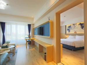 a hotel room with a bed and a flat screen tv at Kyriad Marvelous Hotel Haerbin West High-Speed Railway Station Wanda in Harbin