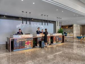 a group of people standing at a counter in a lobby at Kyriad Marvelous Hotel Shanghai International Tourist Resort Pudong Airport in Nanhui