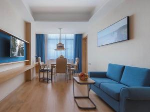 uma sala de estar com um sofá azul e uma mesa em Kyriad Marvelous Hotel Huizhou Boluo Longxi em Boluo